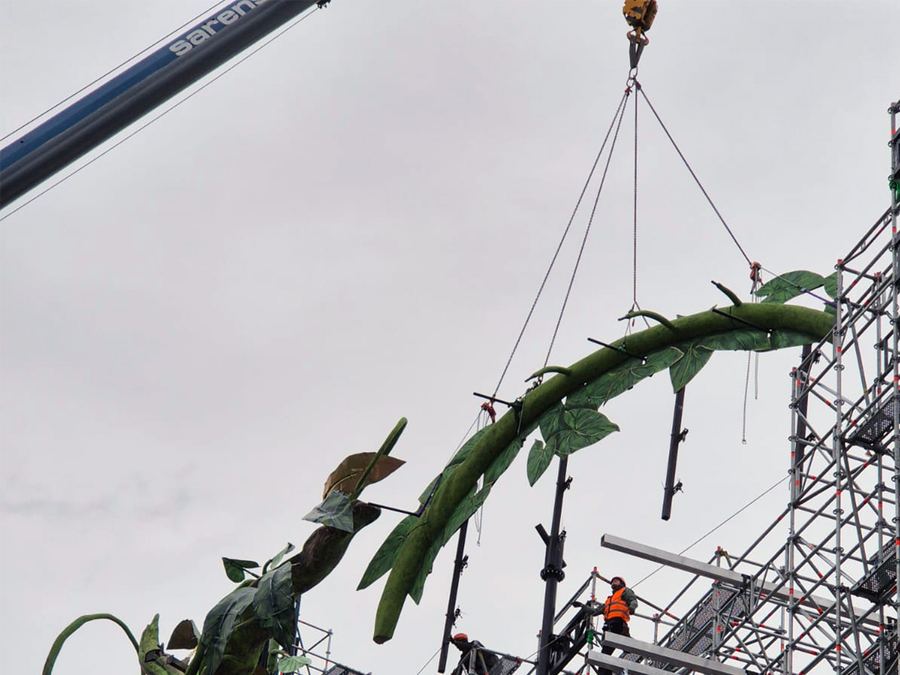Crane lifting a large decorative vine sculpture onto the Tomorrowland stage structure