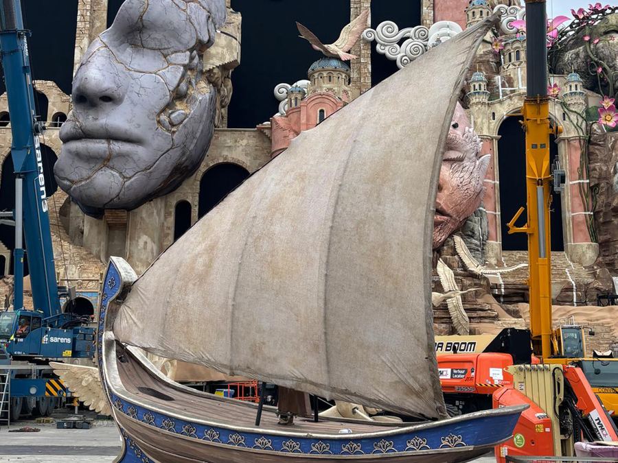 Giant sculpted face and decorative sailboat prop rigged for the Tomorrowland mainstage