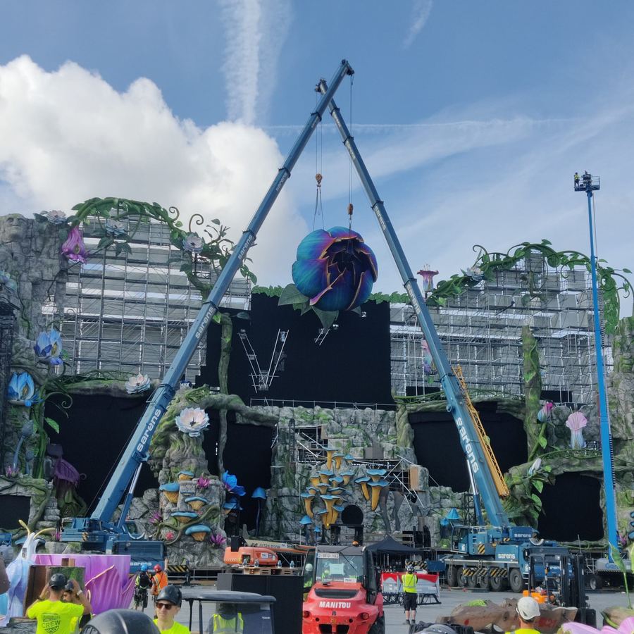 Crane lifting a large decorative flower sculpture onto a festival mainstage
