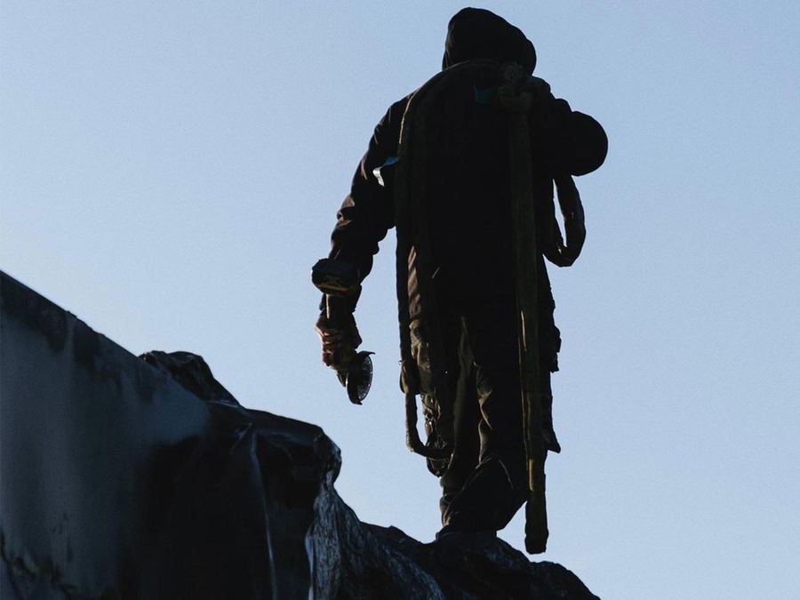 Rigger silhouetted atop a scenic structure at height