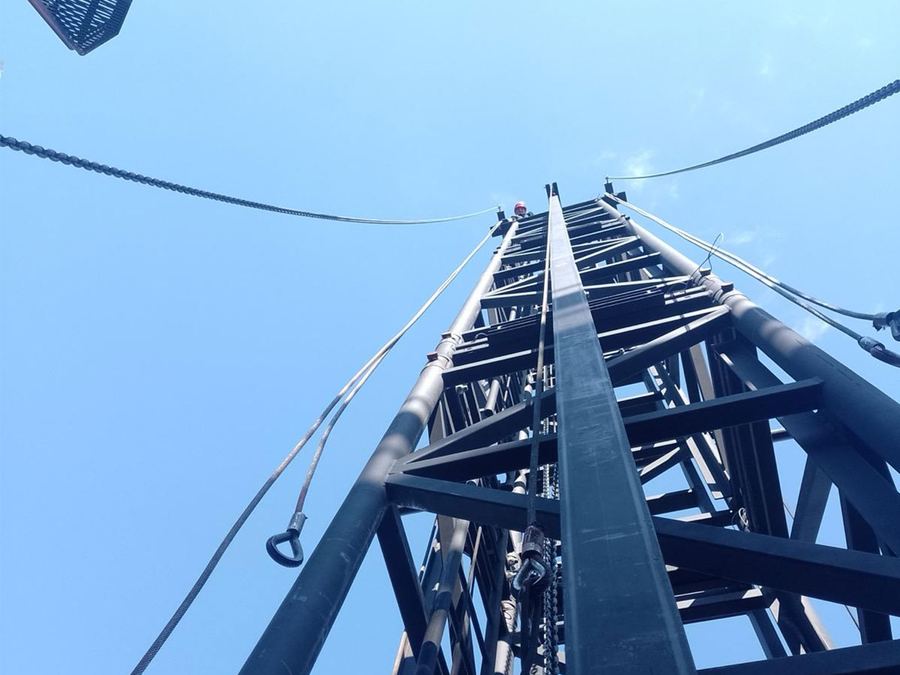 Tall steel lighting truss tower viewed from below against a blue sky